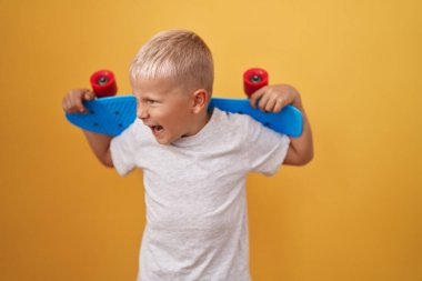 Küçük beyaz çocuk kızgın ve kızgın bir şekilde kaykay tutuyor sinirli ve öfkeliydi, öfkeyle bağırıyordu. öfke ve agresif konsept. 