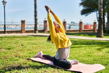 Genç Afrikalı Amerikalı kadın parkta yoga eğitimi alıyor.