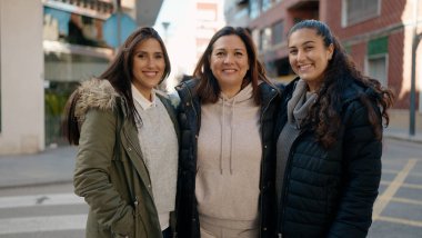 Mother and daugthers smiling confident hugging each other at street
