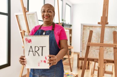 Sanat stüdyosunda resim çizen yaşlı Afro-Amerikan kadın.