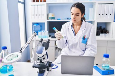 Laboratuvarda çalışan, bilim adamı üniforması giyen genç İspanyol kadın.