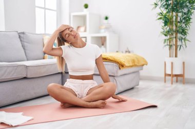 Young beautiful hispanic woman stretching head at home