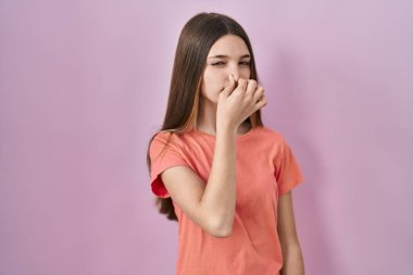 Pembe arka planda duran genç kız pis ve iğrenç bir koku alıyor. Nefesini burnunda tutuyor. Kötü kokuyor. 