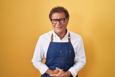 Orta yaşlı İspanyol bir adam midesi üstünde profesyonel bir aşçı önlüğü giyiyor çünkü hazımsızlık, acı verici bir hastalık kendini iyi hissetmiyor. Ağrı kavramı. 