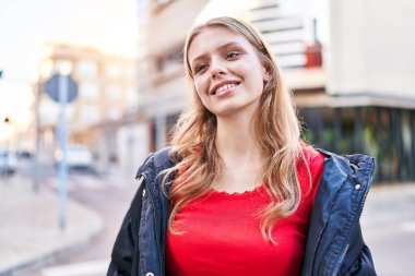 Young blonde woman smiling confident looking to the side at street