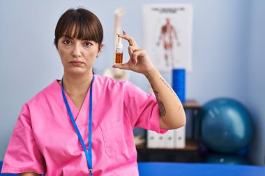 Fizyoterapi kliniğinde elinde cbd yağı tutan genç esmer bir kadın. Düşünce tarzı ve ayık ifadesi. Kendine güvenen biri. 