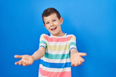 Mavi arka planda duran genç beyaz çocuk gülümseyerek yardım ve kabullenme eli uzatıyor.. 