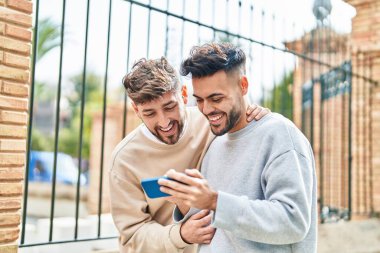 Young couple using smartphone standing together at street