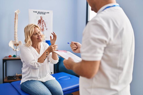 Мужчина и женщина среднего возраста физиотерапевт и пациент, проходящие реабилитацию в клинике физиотерапии