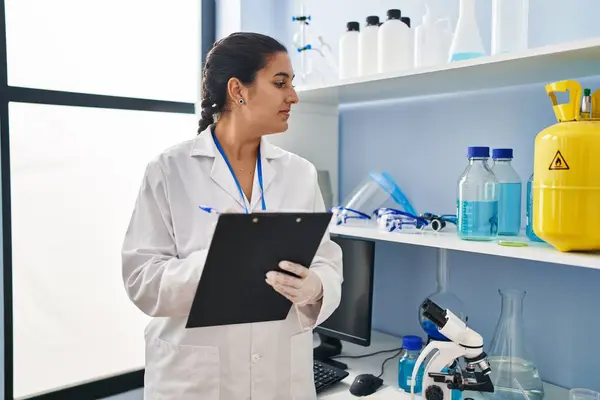 Young Hispanic Woman Wearing Scientist Uniform Writing Clipboard Laboratory — Stock Photo, Image