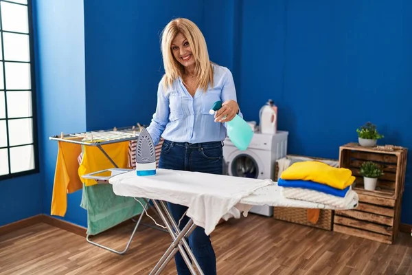 Middle Age Blonde Woman Smiling Confident Ironing Clothes Laundry Room — ストック写真