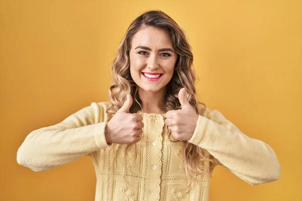 Sarı Arka Plan Başarı Işaretinin Üzerinde Duran Genç Beyaz Kadın — Stok fotoğraf