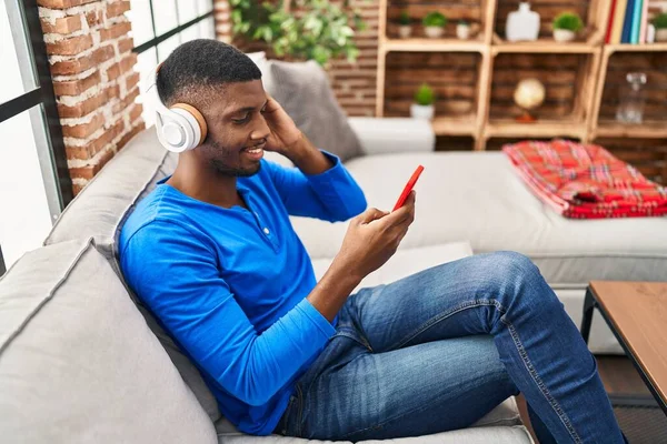 Young African American Man Listening Music Sitting Sofa Home — Stock fotografie