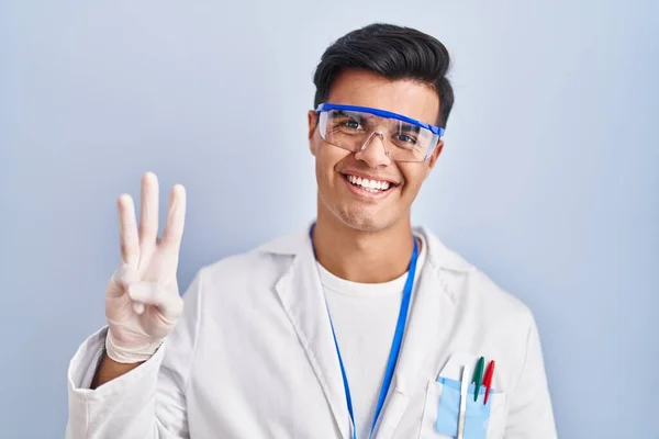 Latynos Pracuje Jako Naukowiec Pokazując Wskazując Palcami Numer Trzy Uśmiechając — Zdjęcie stockowe