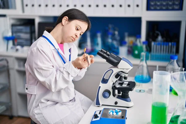 stock image Young woman with down syndrome scientist holding pill at laboratory