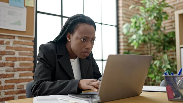 アフリカ系アメリカ人の女性ビジネスワーカーがオフィスでノートパソコンを使って — ストック写真