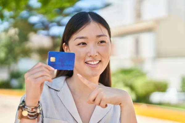 Chinese woman smiling confident pointing with finger to credit card at park
