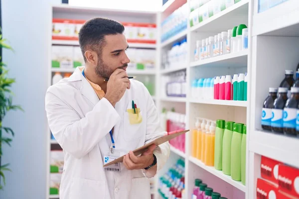 Young Hispanic Man Pharmacist Writing Document Serious Expression Pharmacy — Stock Photo, Image