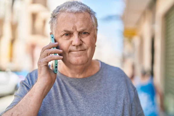 중년의 백발의 남자가 스마트폰으로 편하게 말하며 거리에서 이야기하고 있습니다 — 스톡 사진