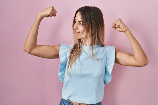 Mujer Hispana Joven Pie Sobre Fondo Rosa Mostrando Los Músculos —  Fotos de Stock