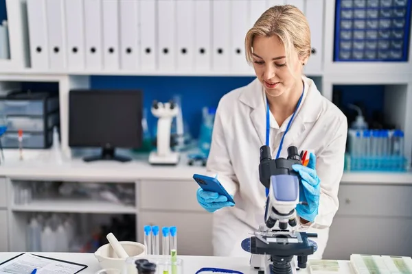 Young Blonde Woman Scientist Using Microscope Smartphone Laboratory — Stockfoto