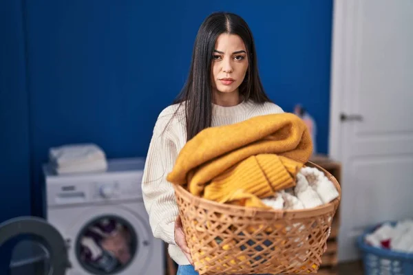 Young woman holding laundry basket depressed and worry for distress, crying angry and afraid. sad expression.