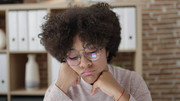 Young african american woman business worker sitting on table with sad expression at office