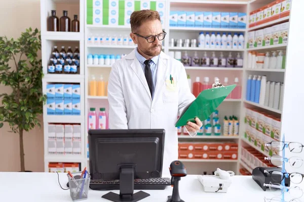 Middle Age Man Pharmacist Reading Document Using Computer Pharmacy — Stockfoto