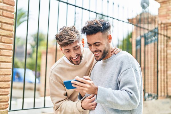 Young couple using smartphone standing together at street