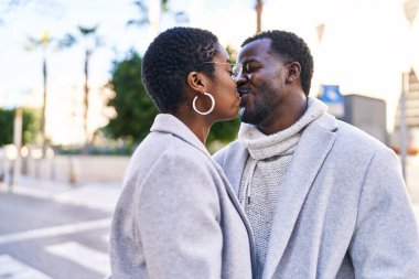 Man and woman couple standing together kissing at street