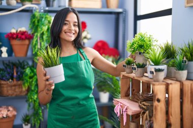 Çiçekçi dükkanında çiçekleri tutarken gülümseyen İspanyol kadın.