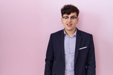 Sakallı, takım elbiseli ve kravatlı genç bir adam kameraya seksi bir ifadeyle bakıyor, neşeli ve mutlu bir yüzü var.. 