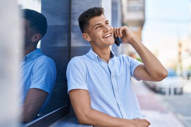 Genç İspanyol adam gülümsüyor. Kendine güveniyor. Sokakta akıllı telefondan konuşuyor.