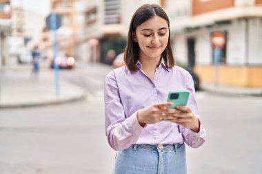 Sokakta akıllı telefon kullanan, kendine güvenen genç İspanyol kadın.