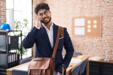 Genç İspanyol iş adamı ofiste akıllı telefondan konuşuyor.