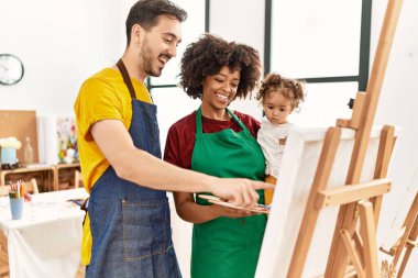 Couple and daughter smiling confident drawing at art studio