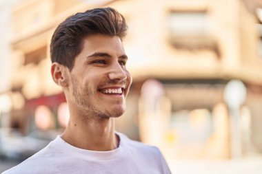 Genç İspanyol adam gülümsüyor parkın kenarına bakıyor.