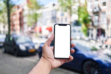 Elinde akıllı telefon tutan adam Amsterdam 'da beyaz boş ekran gösteriyor.