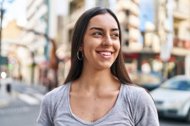 Young beautiful hispanic woman smiling confident looking to the side at street