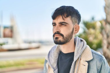 Young hispanic man looking to the side with relaxed expression at street