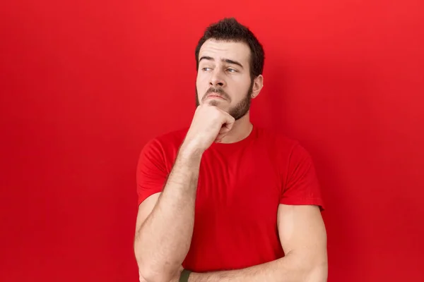 Joven Hombre Hispano Con Camiseta Roja Casual Con Mano Barbilla — Foto de Stock