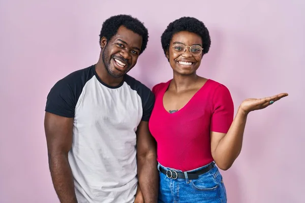 Молодая Африканская Американская Пара Стоящая Розовом Фоне Улыбаясь Веселым Подарком — стоковое фото