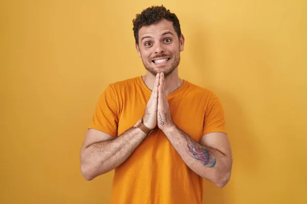 Young Hispanic Man Standing Yellow Background Praying Hands Together Asking — Stock fotografie