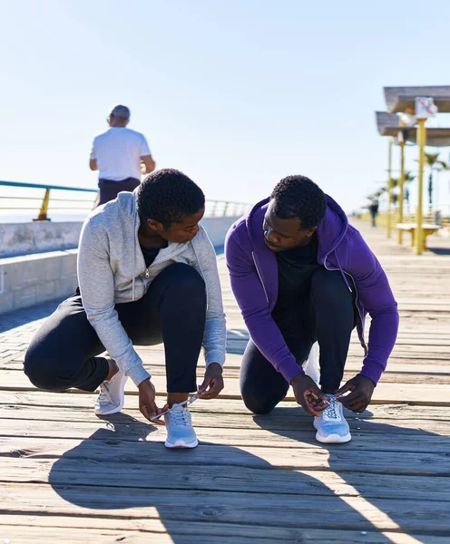 stock image Man and woman couple wearing sportswear tying shoes at seaside