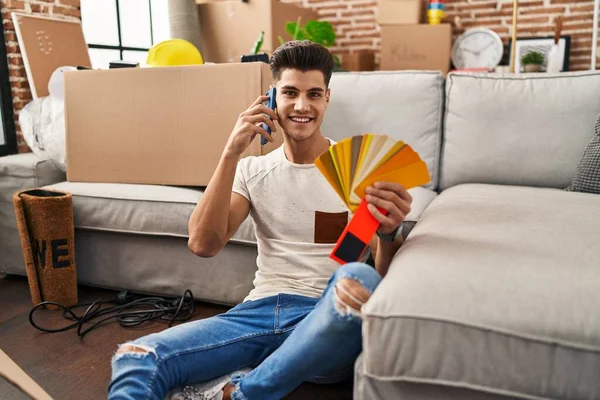 Jonge Spaanse Man Kiezen Verf Kleur Muur Praten Smartphone Nieuw — Stockfoto