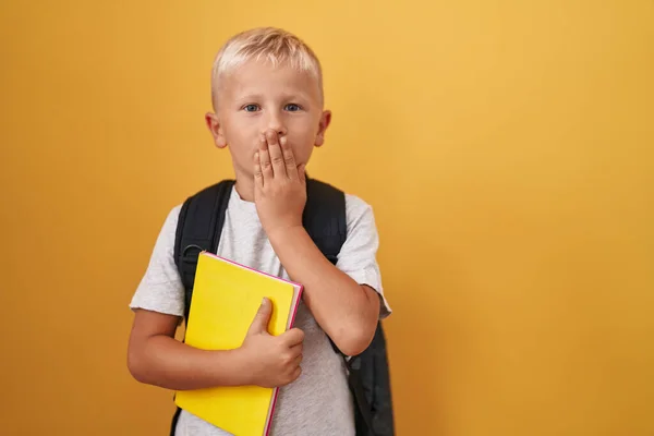 Little Caucasian Boy Wearing Student Backpack Holding Book Covering Mouth — Stockfoto