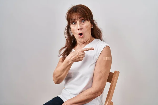 Latynoska Kobieta Średnim Wieku Otrzymująca Szczepionkę Opatrunkiem Zaskoczona Wskazaniem Palcem — Zdjęcie stockowe