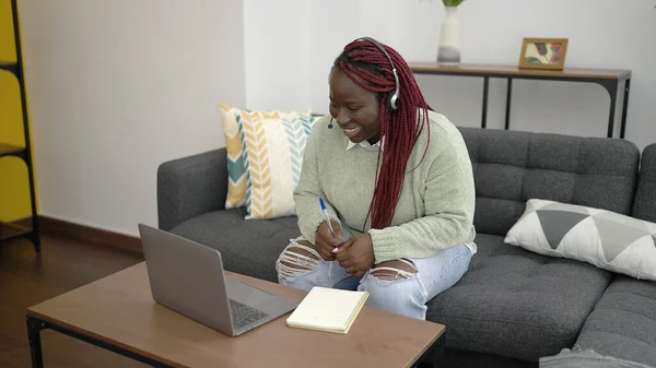 自宅でノートパソコンを使用して自宅から仕事編組髪を持つアフリカの女性は ヘッドセットを身に着けて — ストック写真