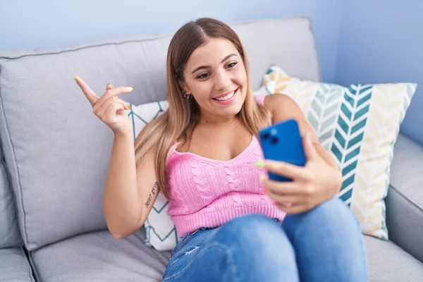 Jovem Loira Fazendo Videochamada Com Smartphone Sentado Sofá Sorrindo Feliz — Fotografia de Stock