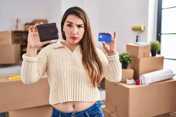 年轻的惊慌失措的女人拿着钱包和信用卡搬到了一个新家 她感到怀疑和紧张 因为问题而皱着眉头 消极的人 — 图库照片